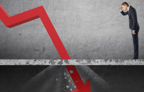 Businessman looking down at the falling red arrow destroying a